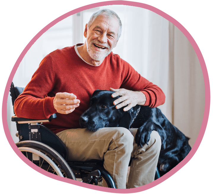 Male client in wheelchair with his black labrador smiling