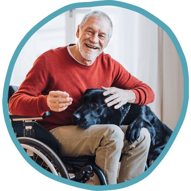 Male client in wheelchair smiling with his black labrador