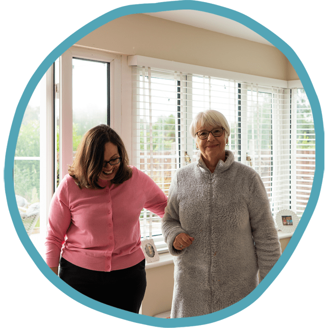 Female carer and female client walking in the conservatory