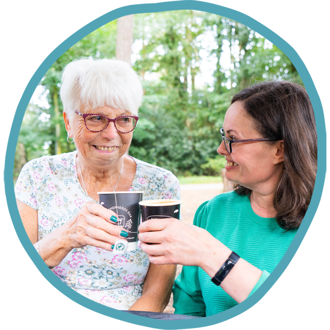 female carer and female client having a drink together out in the park