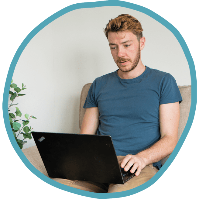 Male carer checking care notes on his work laptop