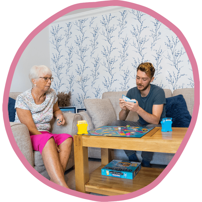 Female client and male carer sat together playing a board game