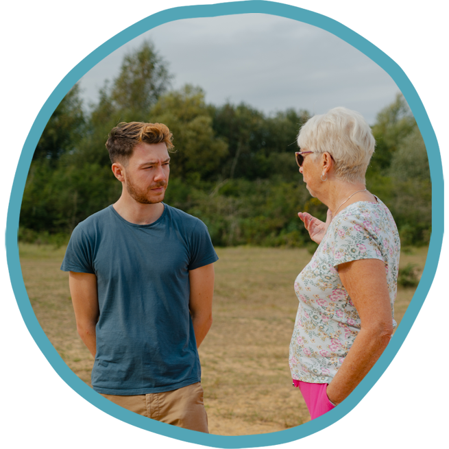 Male carer and female client looking at picked flowers on a park walk together